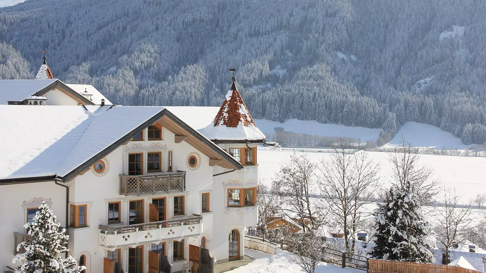 The facade of our 3-star hotel in Val Casies with its snow-capped roof on a sunny winter day.