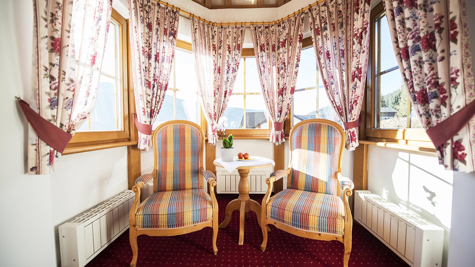 Elegant room in the turret of our hotel in Val Casies with elegant armchairs and large windows