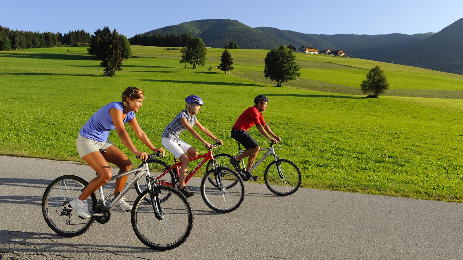 Un gruppo di ciclisti durante una pedalata tra i prati verdi della Val Casies in estate