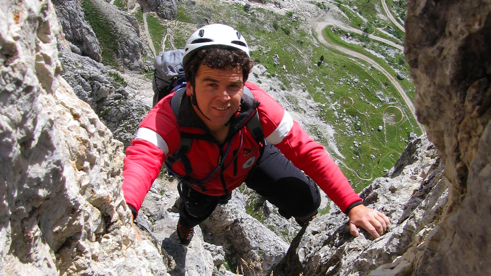Scalatore durante un'escursione in Val Casies con zaino, casco e corda di sicurezza