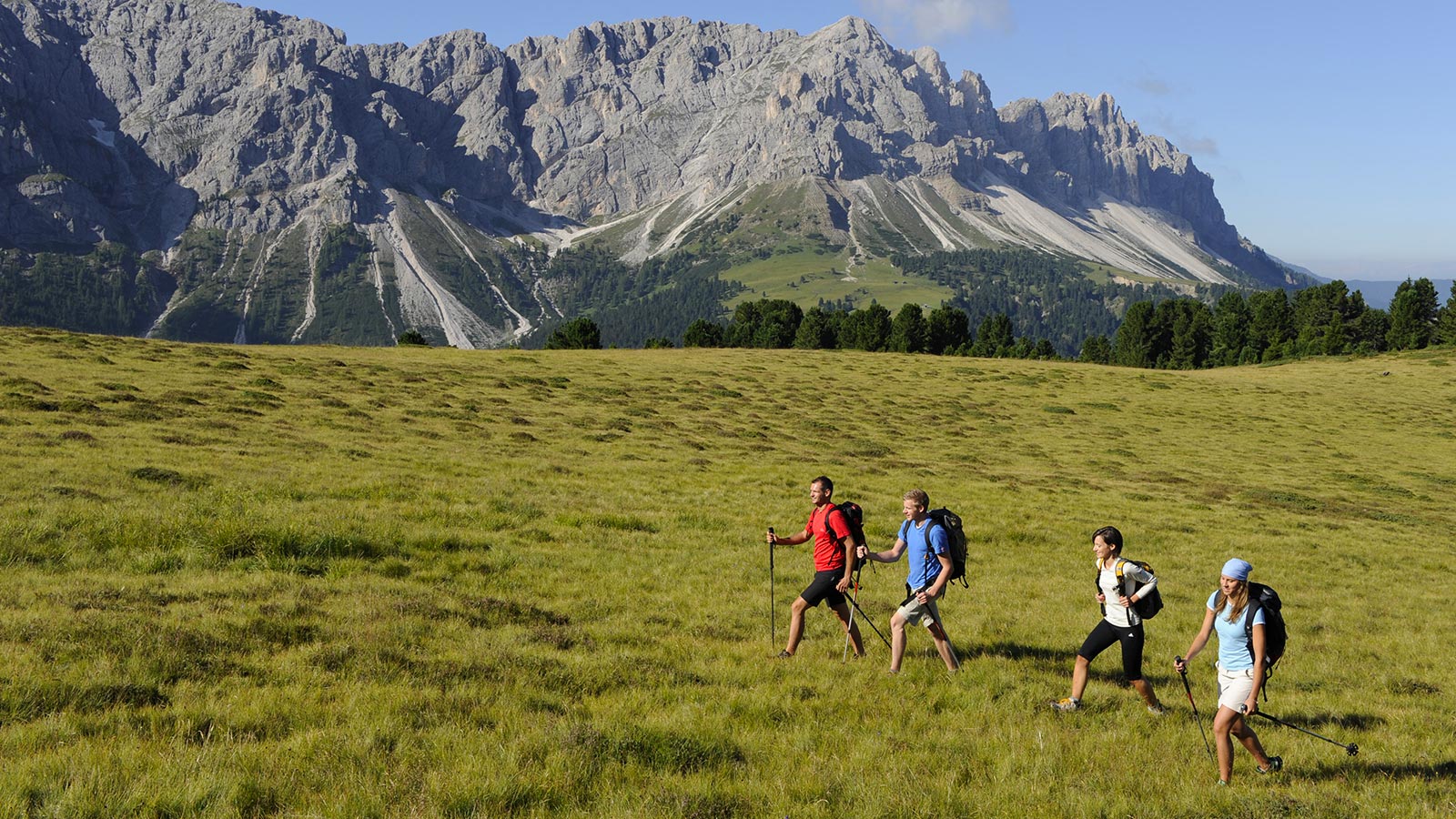 Gruppo di quattro escursionisti sui verdi prati di Plan de Corones con le Dolomiti sullo sfondo