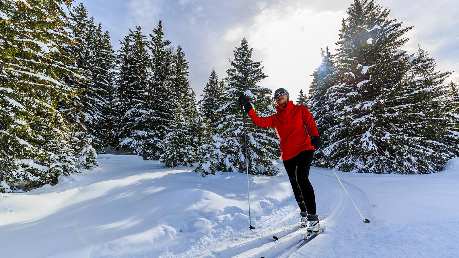 a young lady with a red jacket on a ski tour with cross-country skis