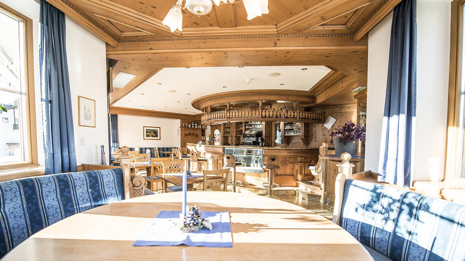 The large dining room of the Hotel Gschwendt in Val Casies with the restaurant bar in the background. 